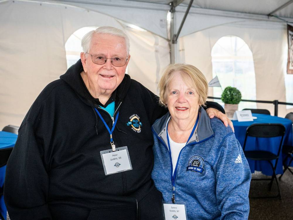 Two alumni from the class of '68 smile for a photo at the Alumni Homecoming Tailgate.